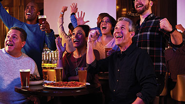 People eating food and watching a sports game